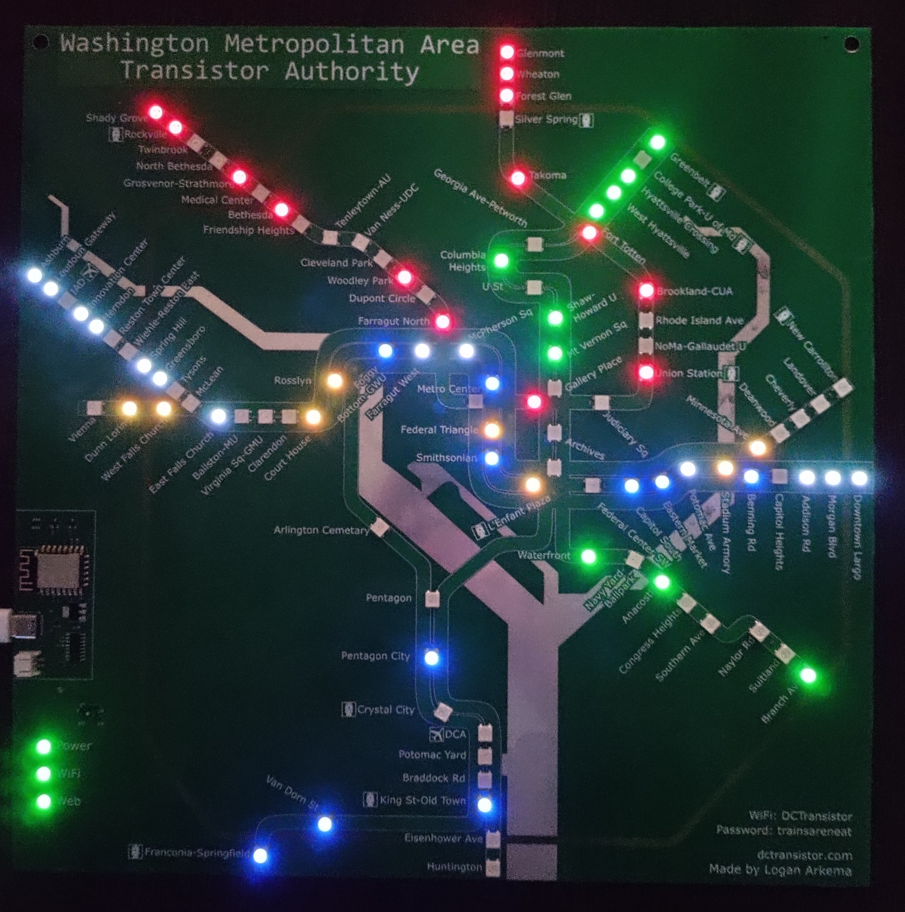 Large picture of a DCTransistor board, powered on to show live train positions. The board is programmable circuit board, mostly light green except for a dark green title and dark green rectangles representing the DC metro train lines, a beige boundary representing the beltway, and silver representing the Potomac and Anacostia rivers. It is designed to represent the DC Metro System map.