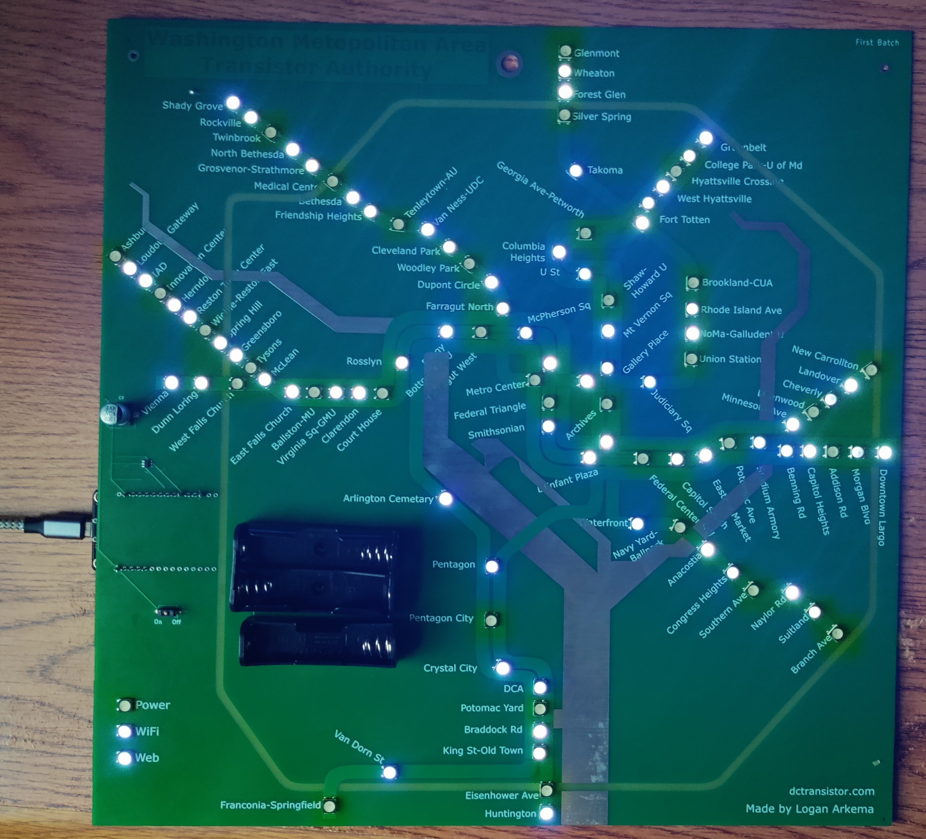 Picture of a DCTransistor board in the middle of a loop through a program that displays a rainbow on the board. On the left side of the picture, a Micro-USB cable is plugged into the chip on the back of the board.